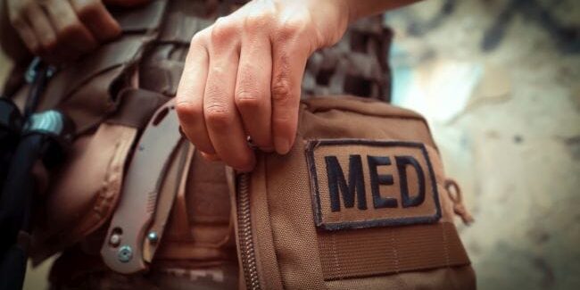 Bild eines Soldaten der an eine Medizintasche greift.